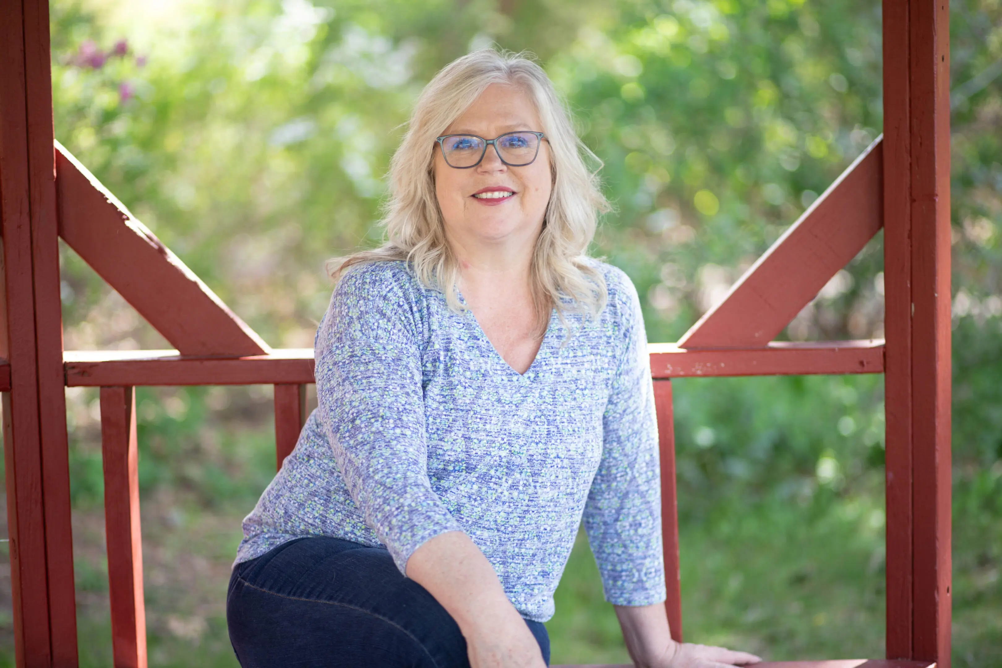 A woman sitting on top of a wooden bench.