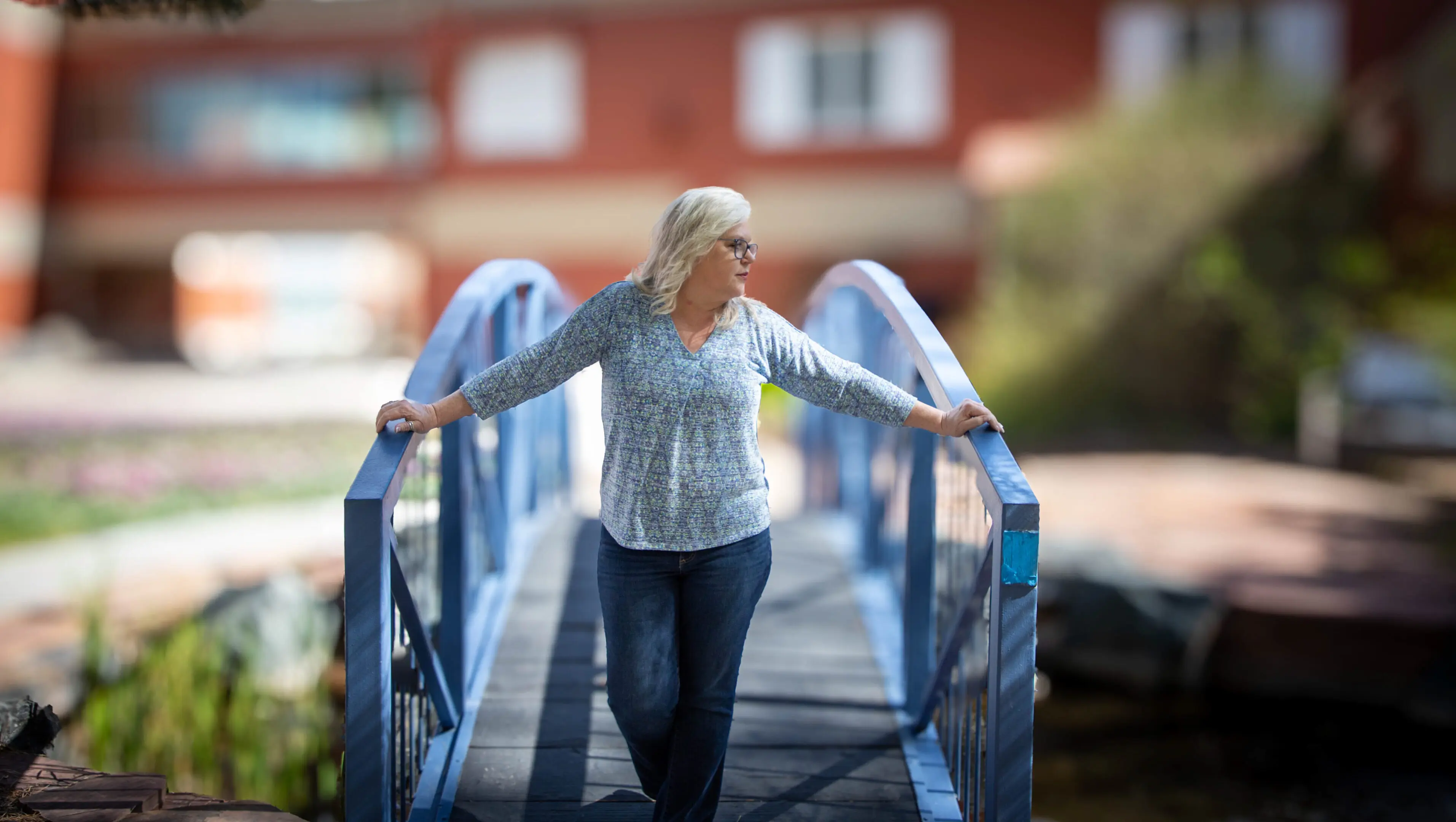 A woman walking across a bridge with her arms outstretched.