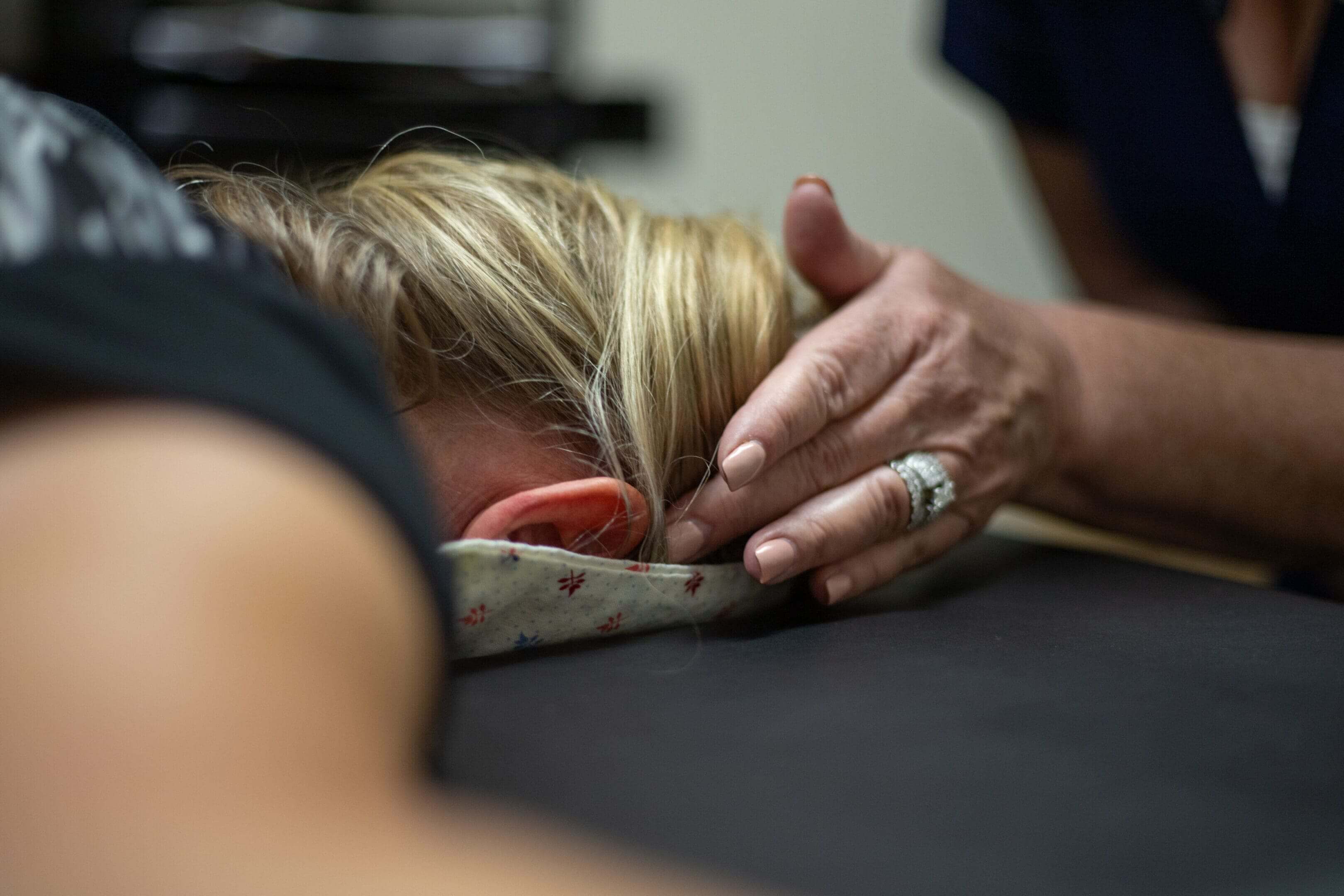 A woman getting her head shaved by an acupuncturist.