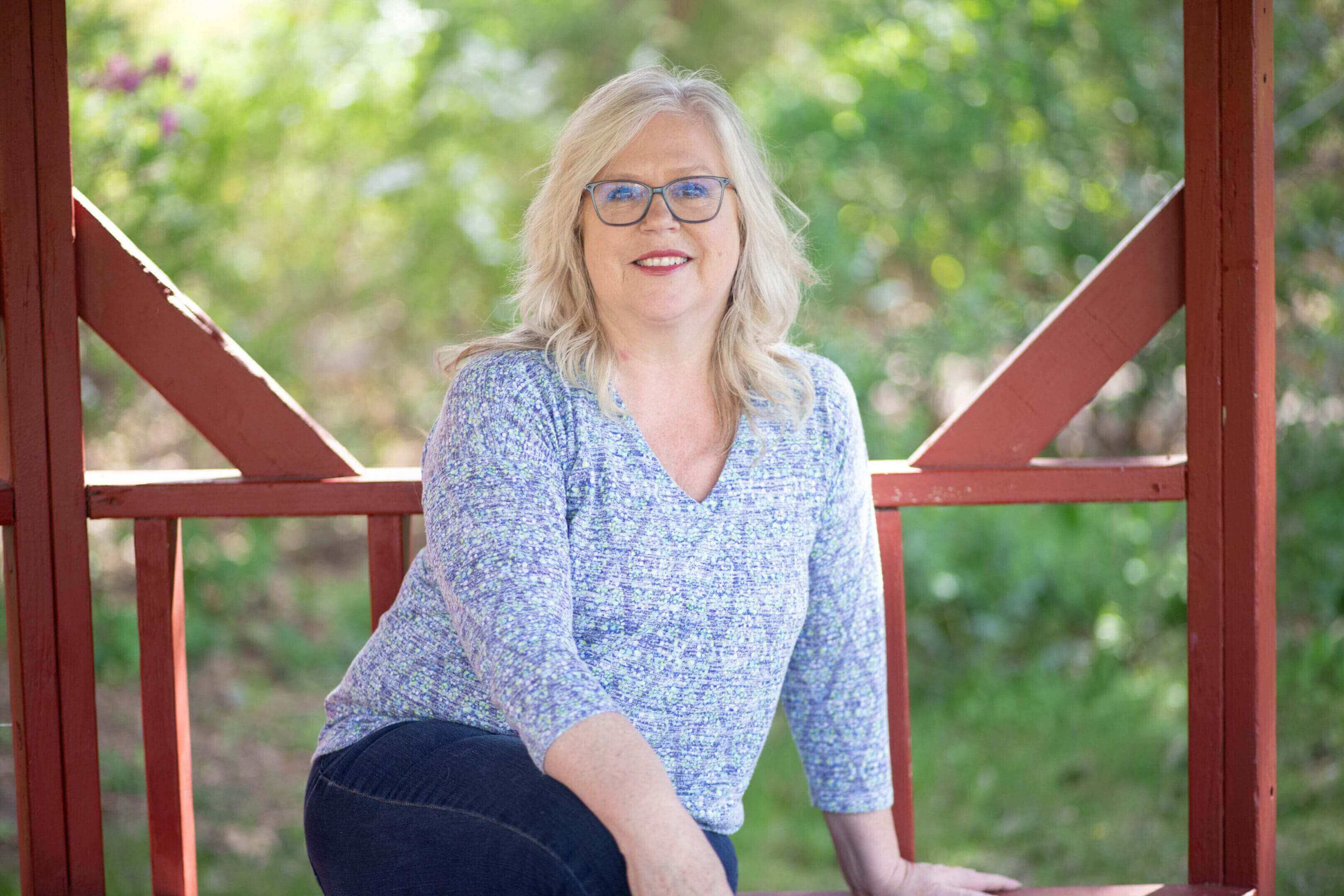 A woman sitting on top of a red bench.